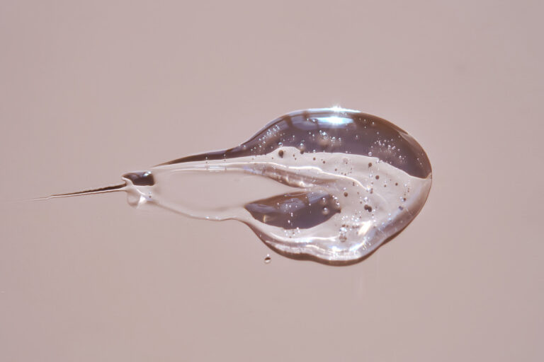 Transparenter Tropfen einer Flüssigkeit vor neutralem Hintergrund