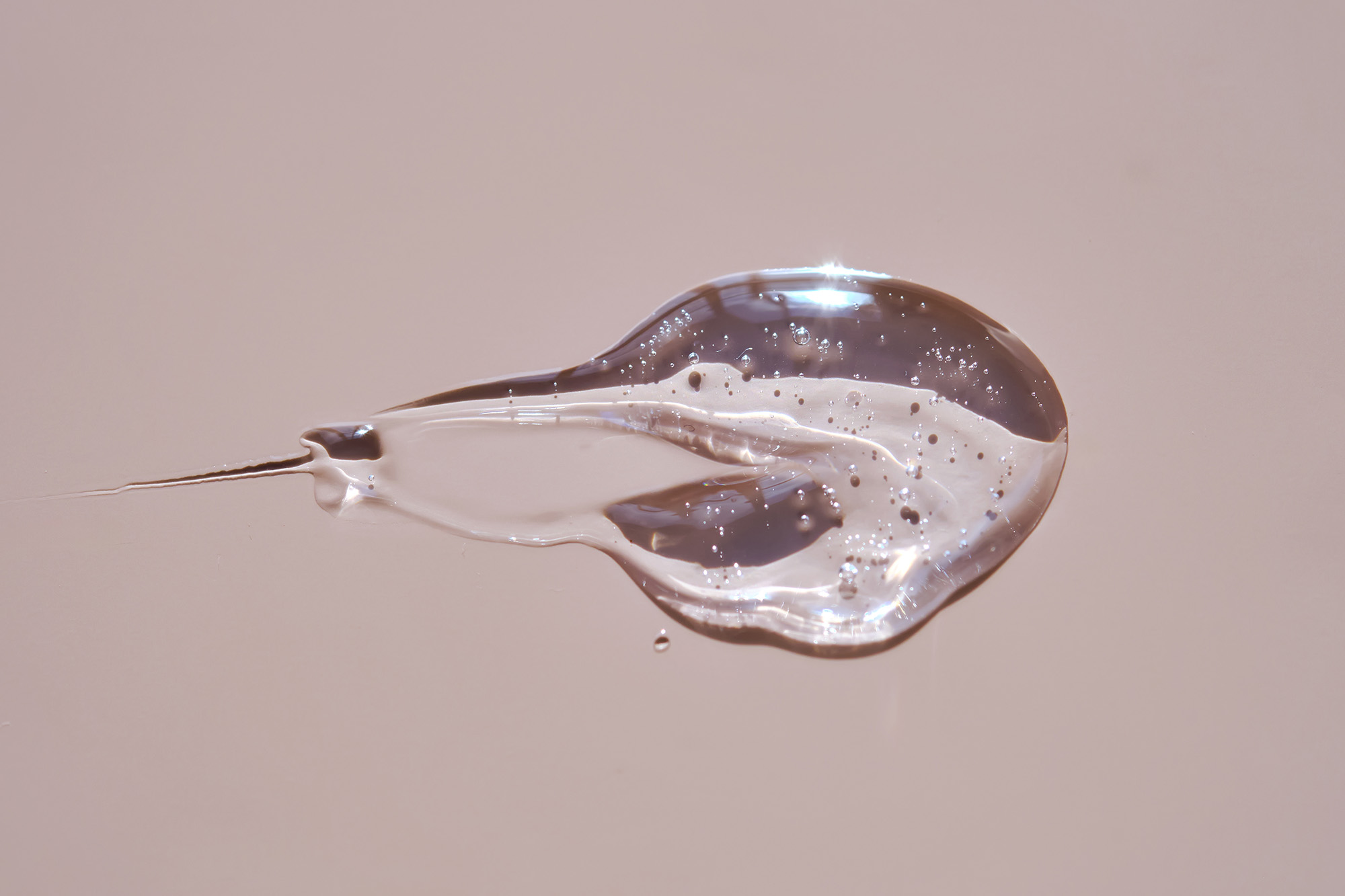 Transparenter Tropfen einer Flüssigkeit vor neutralem Hintergrund