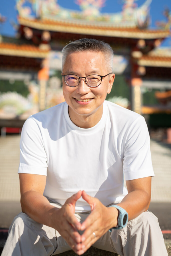 Mann sitzt entspannt vor asiatischem Tempel – Symbolbild für Reisen mit HIV und gute Vorbereitung unterwegs