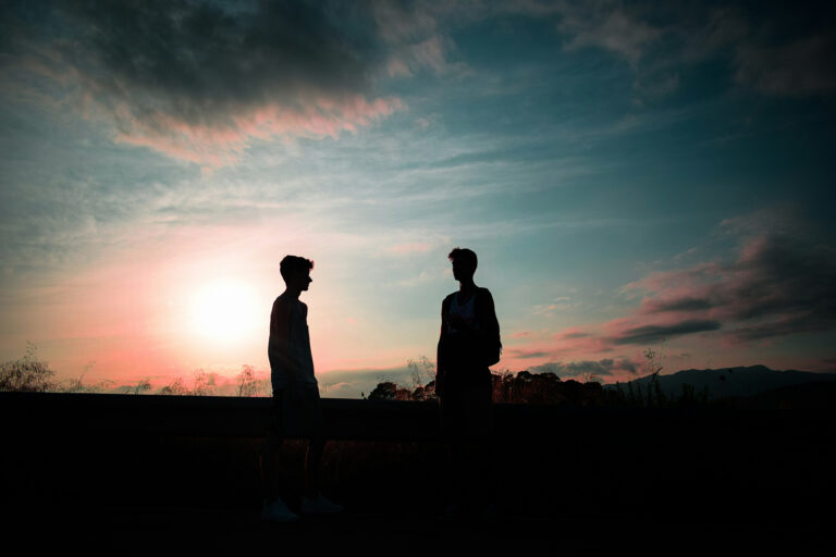 Zwei Menschen stehen sich als Silhouetten im Sonnenuntergang gegenüber – Symbol für Beziehung, Distanz und unterschiedliche Glaubenssätze über Liebe