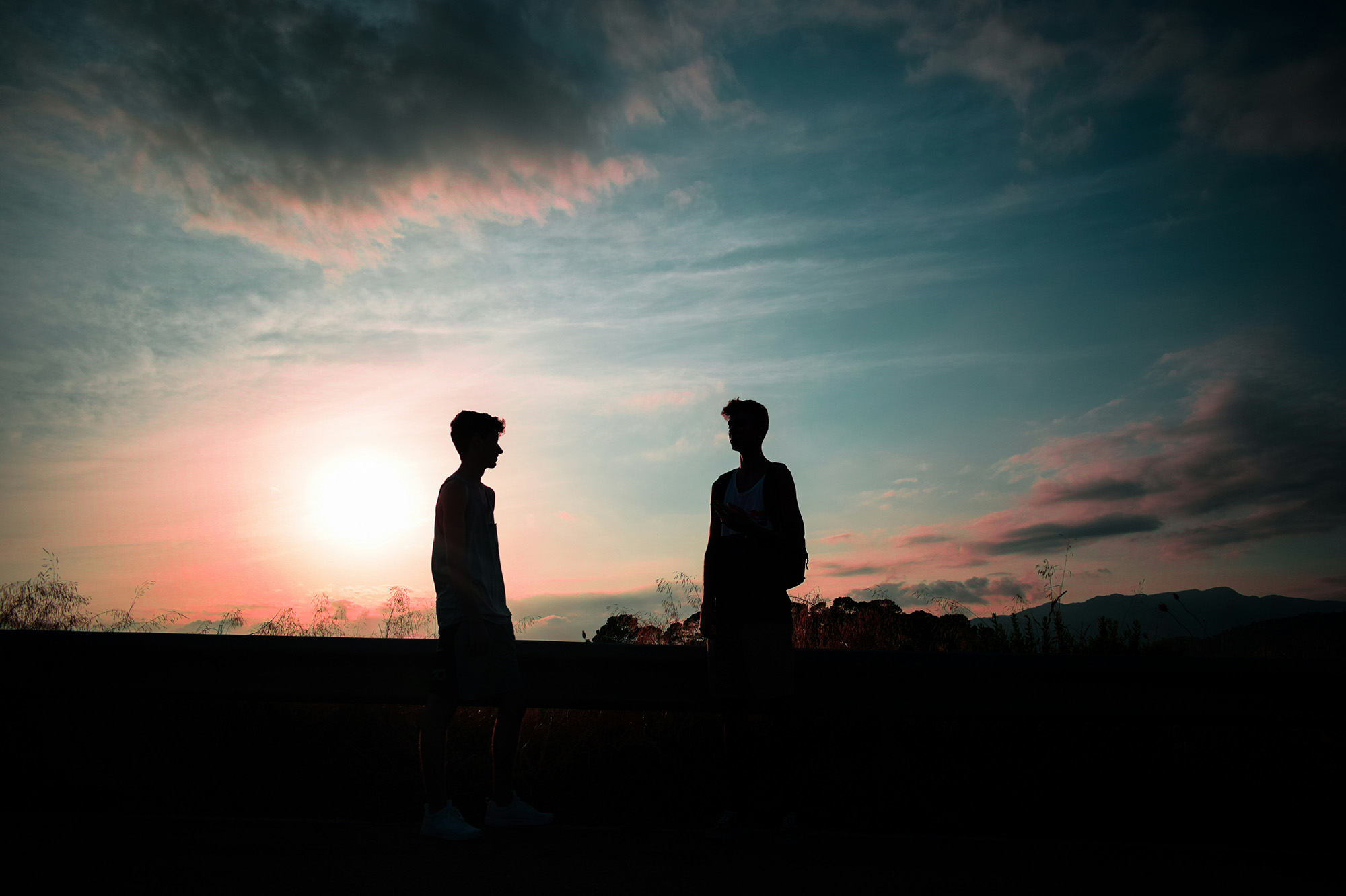 Zwei Menschen stehen sich als Silhouetten im Sonnenuntergang gegenüber – Symbol für Beziehung, Distanz und unterschiedliche Glaubenssätze über Liebe