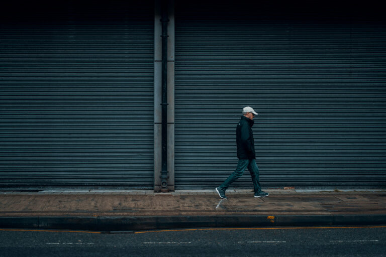 Mann läuft allein an geschlossener Hauswand in der Stadt – Symbol für Einsamkeit und psychische Belastung bei Alkoholkonsum unter Männern