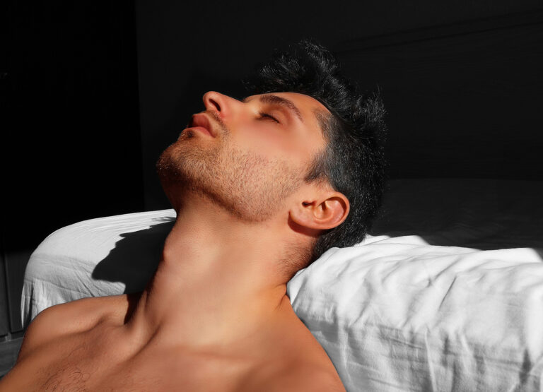 Physiotherapeut im Gespräch: Mann mit nacktem Oberkörper entspannt im Sonnenlicht, Kopf nach hinten gelehnt, ruhige und reflektierte Atmosphäre