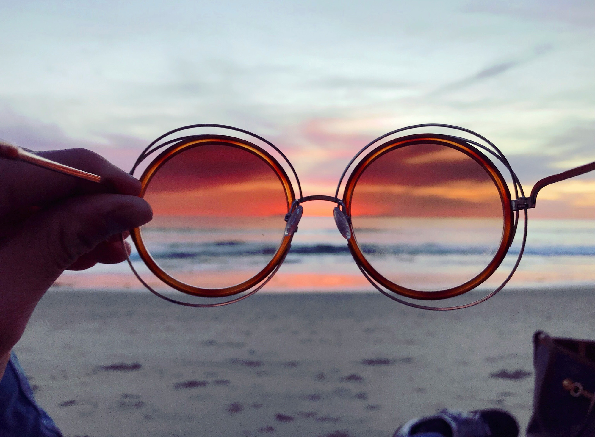 Brille vor einem Sonnenuntergang am Strand als Symbol für Perspektive und Prioritäten im Leben.