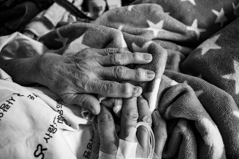 Alte und junge Hand halten sich im Krankenhaus – Symbolbild für Selbstbestimmung, Patientenverfügung und Entscheidungen am Lebensende.